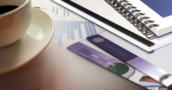 Binding supplies on an office desk next to a coffee mug.