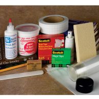 A standard book care and repair kit displayed with adhesive, book cleaner, tapes, erasers, a bone folder, and cleaning supplies organized around a small stack of books.