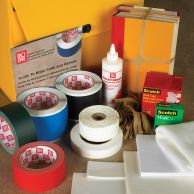 A deluxe book repair kit featuring a variety of colored tapes, adhesives, label protectors, rubber bands, and a repair guide, all arranged next to a stack of bundled books and a yellow storage case.