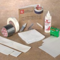 Basic Book Repair Kits displayed with adhesive tapes, liquid adhesive, a cloth, repair strips, a bone folder, Scotch Magic tape, and a guide to book care and repair.