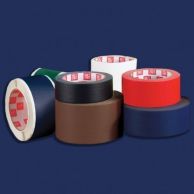 A collection of adhesive tapes in various colors, featuring a roll of blue fabric book repair tape in the front row next to brown, red, black, green, and white rolls.