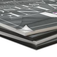 A stack of MountCor Low Temp Pouch Mounting Boards, with the top board partially peeled to reveal its adhesive surface.