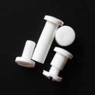 White Plastic Snap Lock Screw Posts displayed in various positions on a black textured surface, showing the interlocking threaded design and flat round heads used for binding loose materials securely.