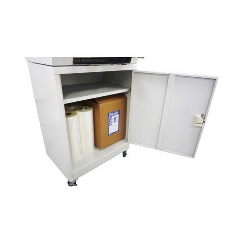 A gray cabinet with an open door shows two shelves, one holding a roll of film and a cardboard box, while the top of the cabinet appears to hold a machine.