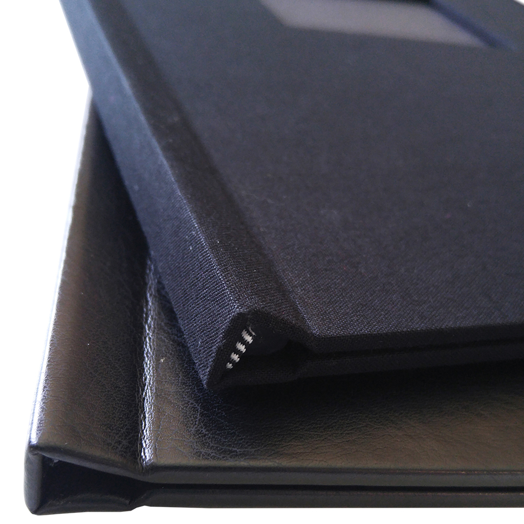 Close-up of two stacked Black Pinchbook photo books, showcasing their durable spine and sleek black covers.