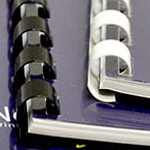 Close-up of plastic comb bound reports with black and white bindings on a dark blue background.