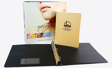 Custom ring binders displayed with a closed beige binder and an open black binder showcasing its metal rings.