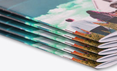 A stack of colorful booklets featuring an outdoor scene with people walking in a park.