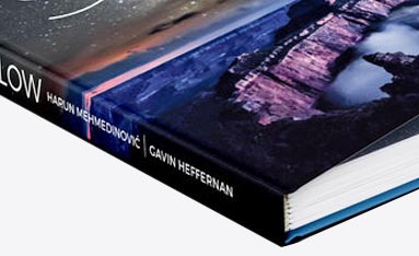 A Fastbind hard cover bound book titled "GLOW" by Harun Mehmedinović and Gavin Heffernan, featuring a landscape scene under a starry night sky.
