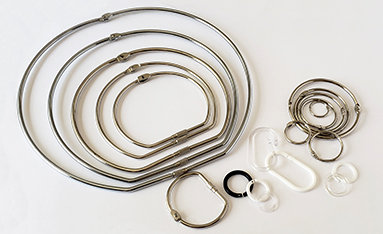 A collection of various sizes of metal and plastic binding rings arranged on a white background.