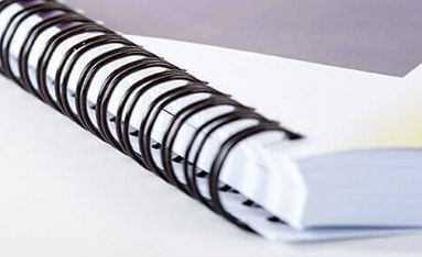 Close-up of twin-loop wire bound documents with a white cover.