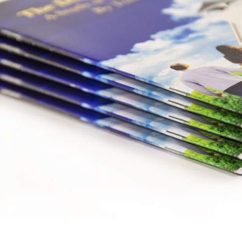 A close-up image of neatly stacked, saddle-stitched booklets with vibrant covers.